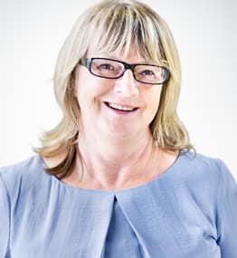 A woman with glasses smiling for the camera.