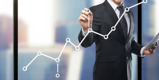 A man in a suit writing on a graph.