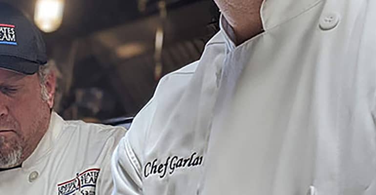A chef is standing in front of some other chefs.
