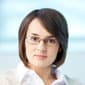 A woman with glasses and short hair wearing a white shirt.